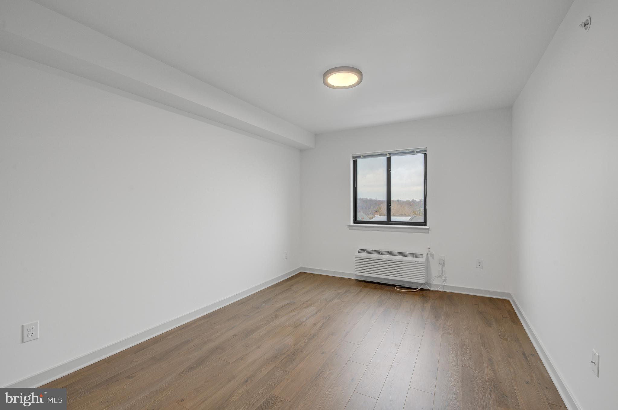 6808 Ridge Avenue, Unit 218 Philadelphia, PA 19128 - Photo 7 of 10 an empty room with wooden floor and windows