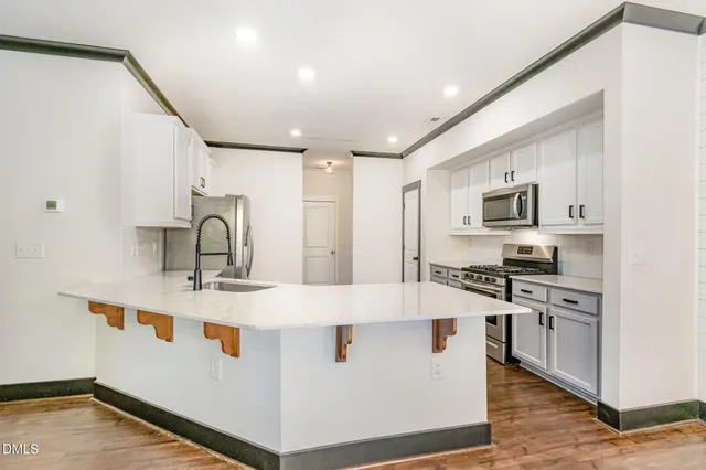 a large white kitchen with stainless steel appliances granite countertop a stove and a sink