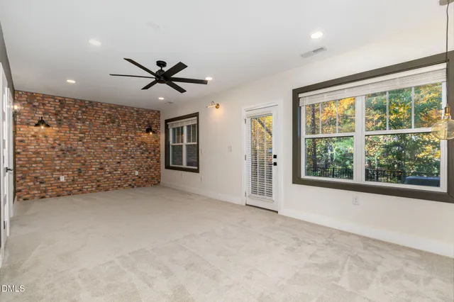 an empty room with windows and ceiling fan