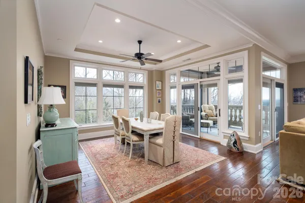a dining room with wooden floor and large windows