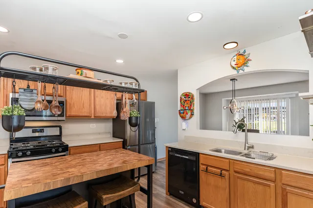 a kitchen with stainless steel appliances a stove a sink dishwasher and cabinets with wooden floor