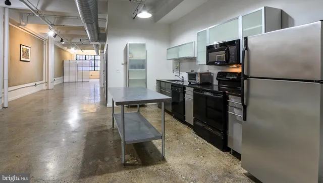 a view of a kitchen with kitchen island a counter top space a sink stainless steel appliances and cabinets