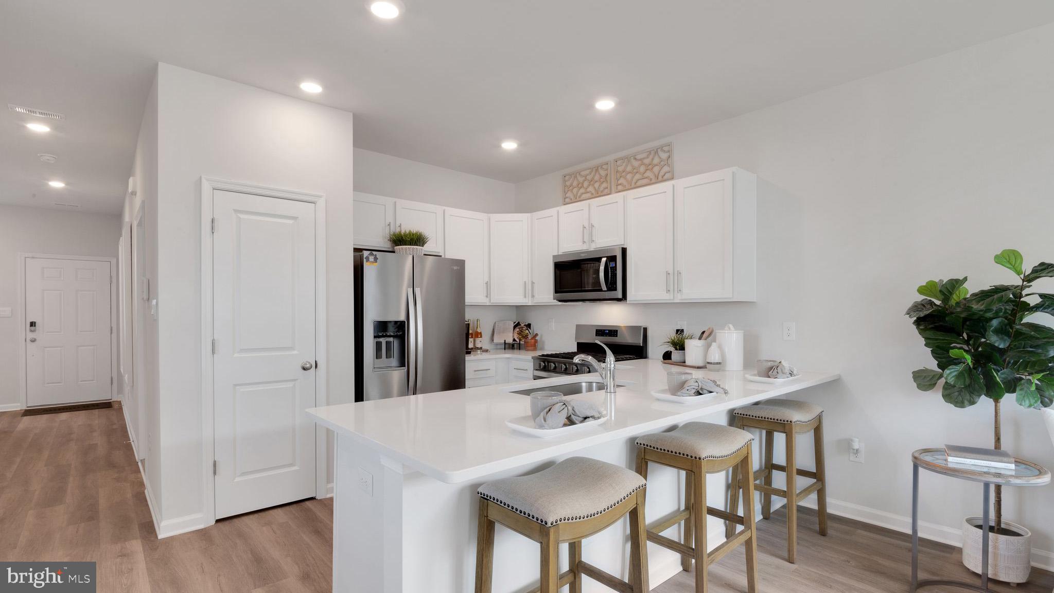 8 Whaler Drive Runnemede, NJ 08078 - Photo 5 of 24 a kitchen with stainless steel appliances kitchen island granite countertop a refrigerator a sink a stove a dining table and chairs with wooden floor