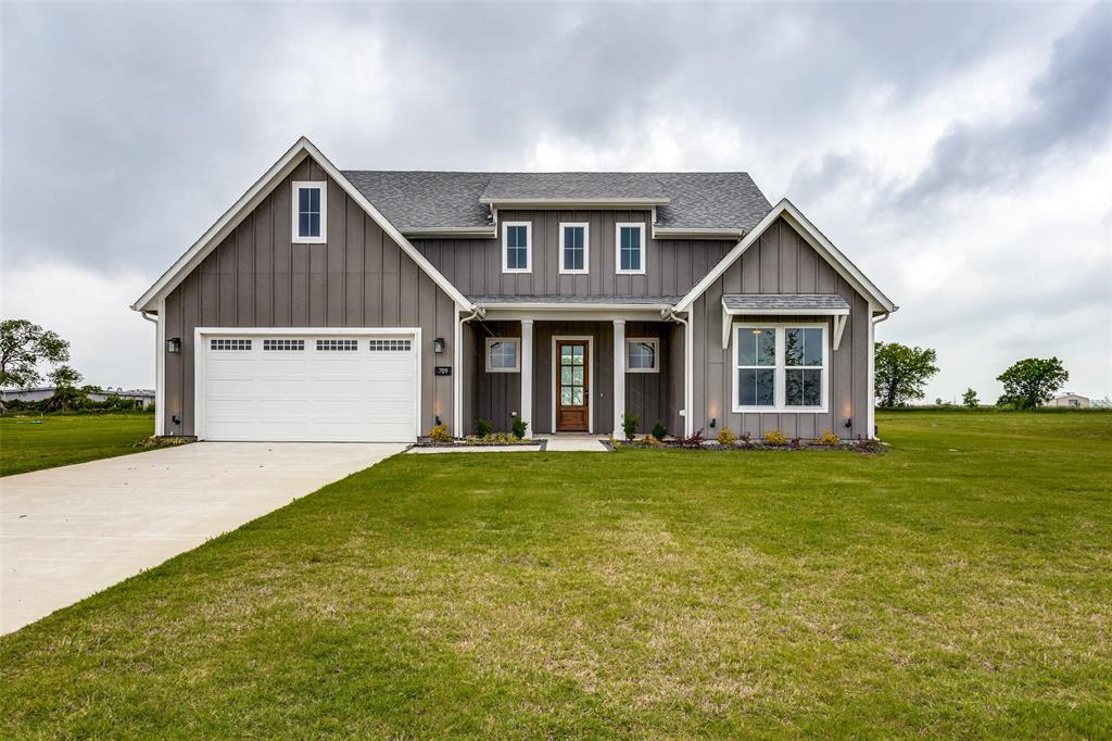 Craftsman-style house with board and batten siding, a front yard, a porch, driveway, and a garage