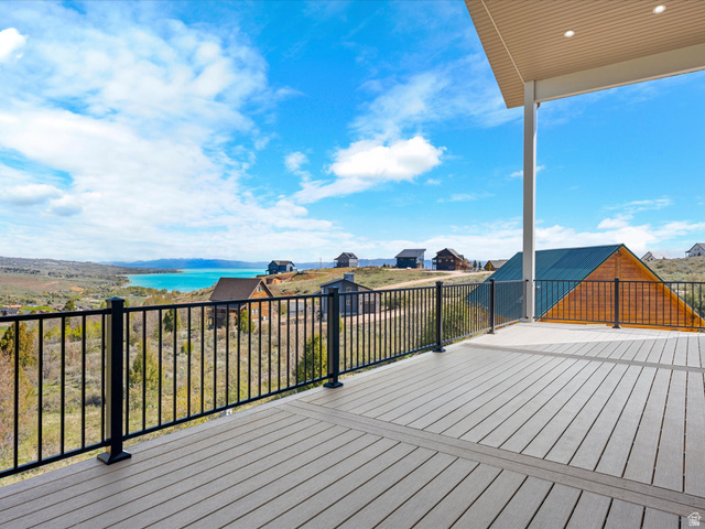 1159 North Broad Hollow Road Garden City, UT 84028 - Photo 3 of 55 Expansive outdoor decking with composite wood-finish flooring, featuring a black metal railing system, covered patio area with recessed lighting, and a panoramic lake and mountain backdrop