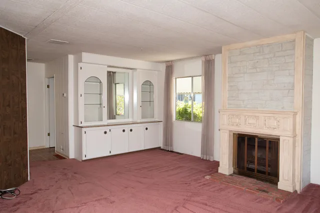 an empty room with windows and fireplace