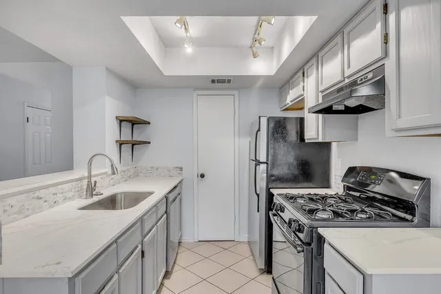 a kitchen with stainless steel appliances granite countertop a sink stove refrigerator and cabinets