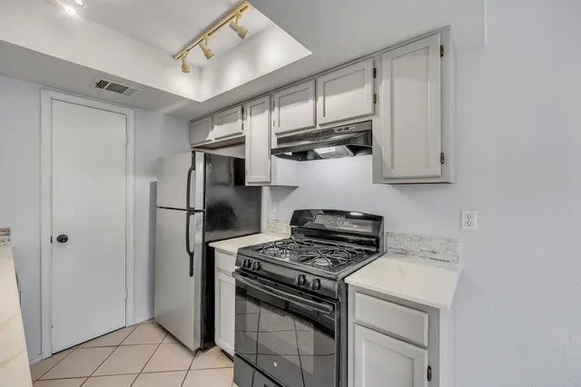 a kitchen with stainless steel appliances white cabinets and a stove top oven