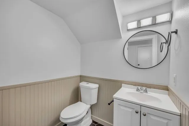 a bathroom with a toilet sink vanity and mirror