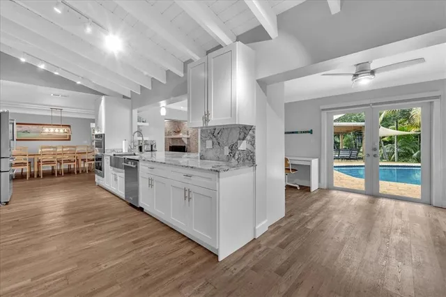 a large white kitchen with lots of counter space a sink and stainless steel appliances