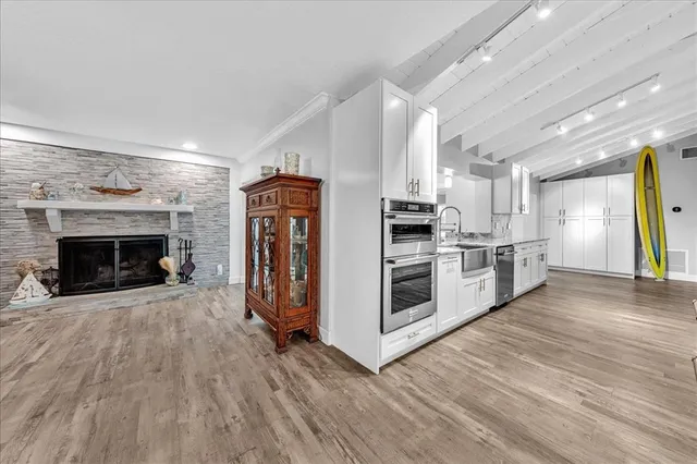 a view of a kitchen with stainless steel appliances wooden floor and a fireplace