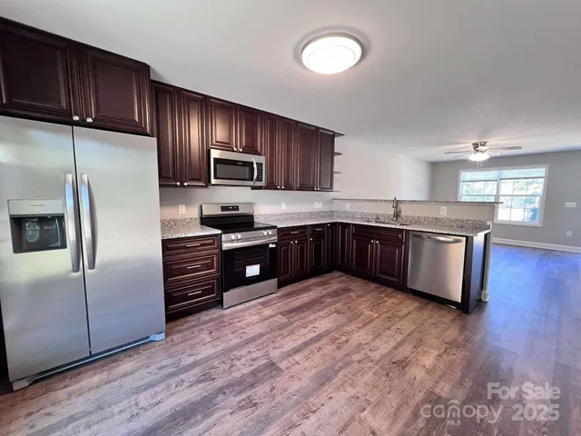 a kitchen with stainless steel appliances granite countertop a refrigerator and a stove top oven