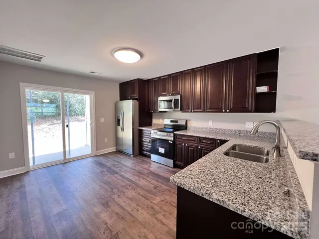 a kitchen with stainless steel appliances granite countertop a sink refrigerator stove and microwave