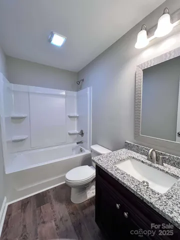 a bathroom with a granite countertop sink toilet mirror and bathtub