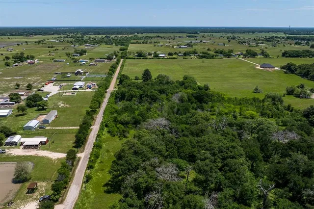 an aerial view of residential houses with outdoor space and trees