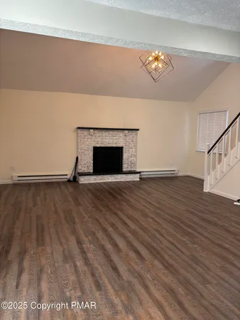 a view of empty room with wooden floor and fireplace