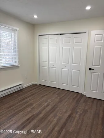 an empty room with wooden floor and closet area
