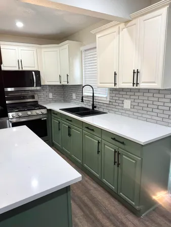 a kitchen with stainless steel appliances a sink dishwasher a stove and white cabinets with wooden floor