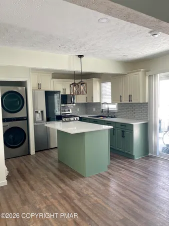 a kitchen with kitchen island granite countertop a sink cabinets and stainless steel appliances