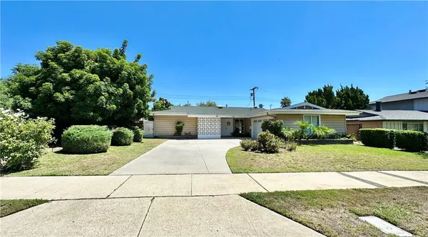 a front view of a house with a yard and potted plants