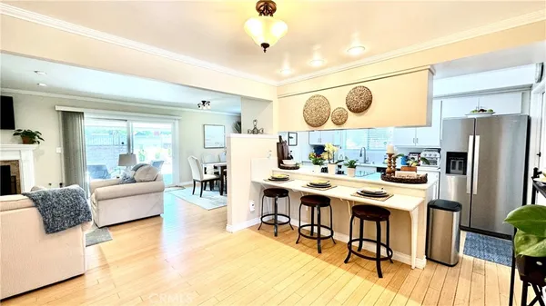 a kitchen with stainless steel appliances granite countertop a stove a refrigerator a dining table and chairs with wooden floor