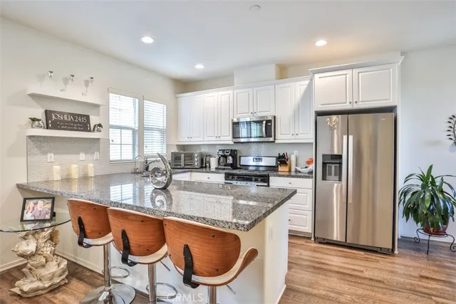 a kitchen with stainless steel appliances granite countertop a sink a stove a refrigerator cabinets and dining table
