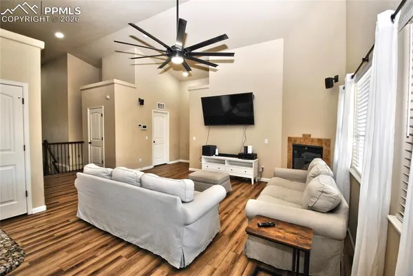 a living room with furniture a flat screen tv and a ceiling fan