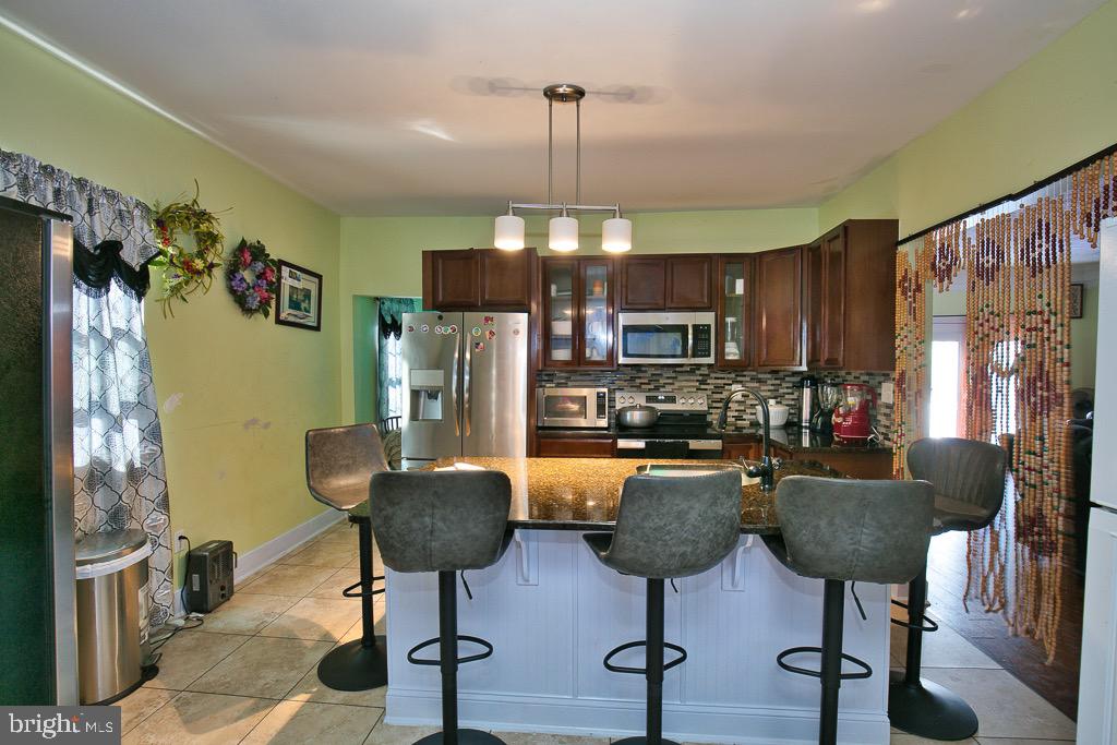 430 Priscilla Street Salisbury, MD 21804 - Photo 32 of 60 a kitchen with stainless steel appliances granite countertop a refrigerator a stove a dining table and chairs with wooden floor