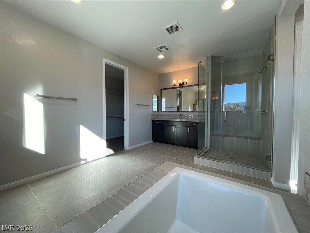 11 Rancho Maria Street Las Vegas, NV 89148 - Photo 16 of 27 A deep soaking tub highlights this modern bathroom with a glass-enclosed shower and dual-sink vanity.