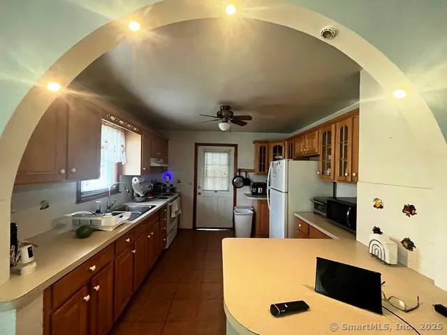 a kitchen with stainless steel appliances kitchen island granite countertop a sink a stove and a refrigerator