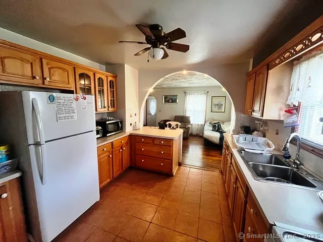 a kitchen with stainless steel appliances a stove a refrigerator a sink a dining table and chairs with wooden floor