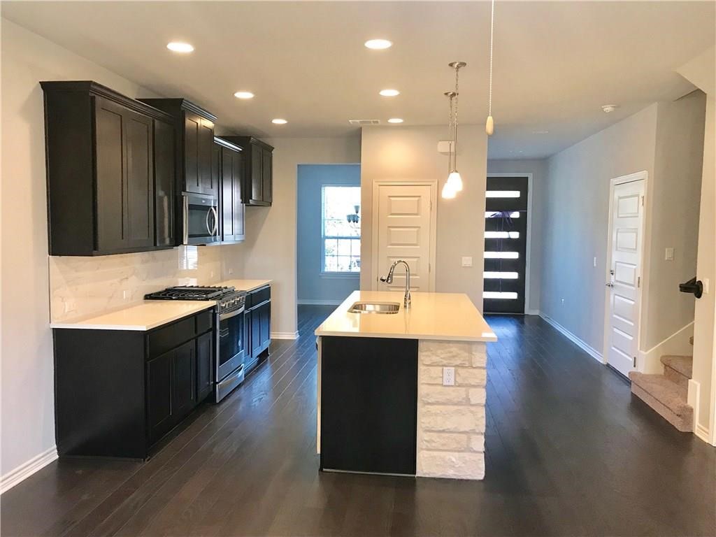 a kitchen with kitchen island sink stove and wooden floor