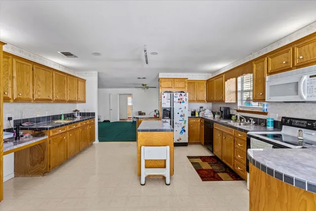 a kitchen with stainless steel appliances granite countertop a stove top oven a sink a dining table and chairs