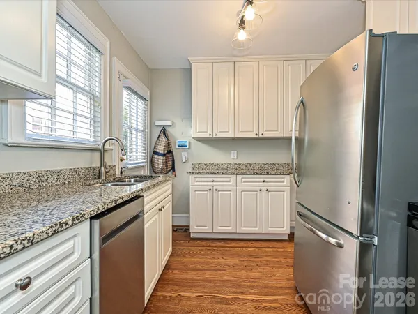 a kitchen with granite countertop a refrigerator sink and cabinets