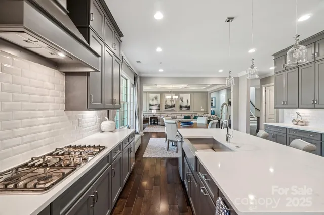 a large kitchen with a large counter top space a sink stainless steel appliances and cabinets