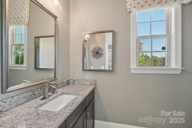 a bathroom with a granite countertop sink a large mirror and a window