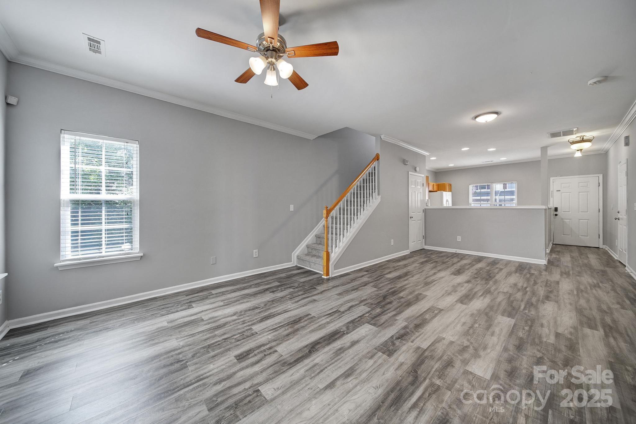 13719 Singleleaf Lane Charlotte, NC 28278 - Photo 16 of 42 an empty room with wooden floor chandelier fan and windows
