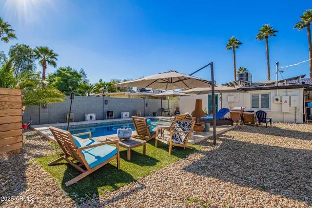 a view of a patio with table and chairs under an umbrella with potted plants
