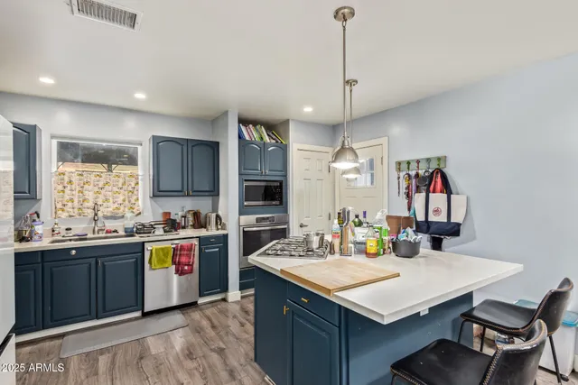 a kitchen with a stove a sink dishwasher and a refrigerator with wooden floor