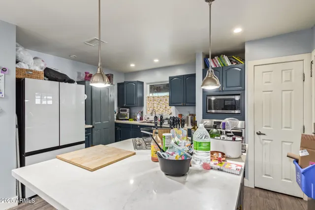 a kitchen with stainless steel appliances kitchen island granite countertop a refrigerator a stove a microwave oven a sink with a dining table and chairs