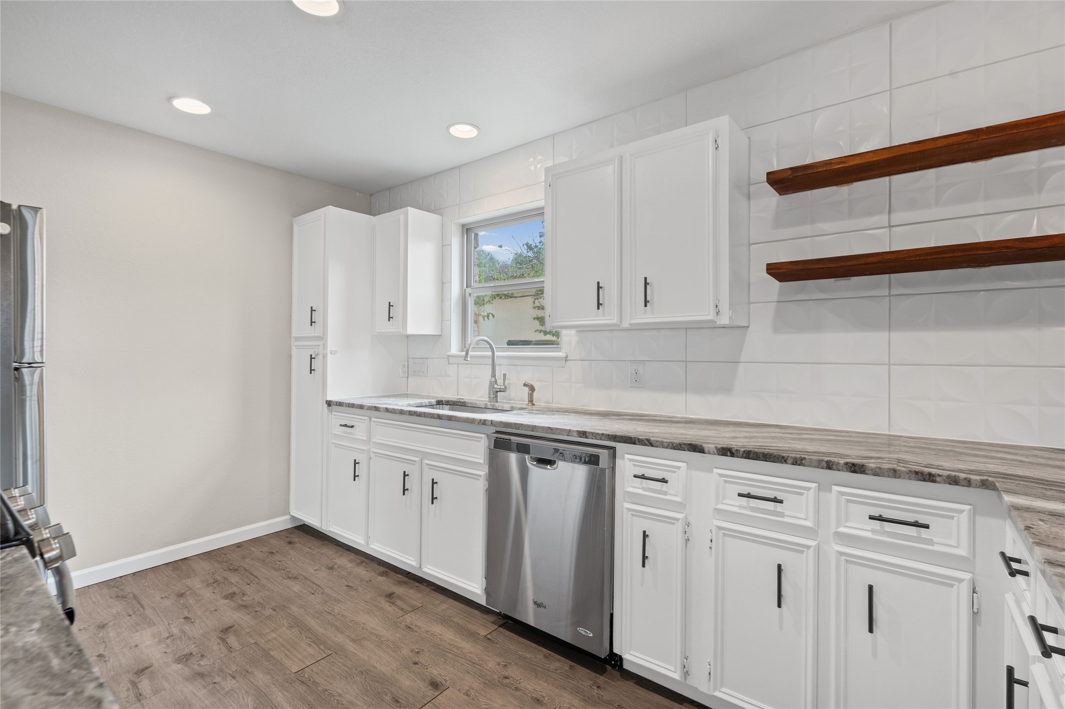 810 Stillhouse Spring Round Rock, TX 78681 - Photo 4 of 18 A well-lit kitchen boasts elegant white cabinetry, sleek countertops, and rich wood flooring.