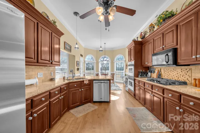 a large kitchen with stainless steel appliances granite countertop a sink and dishwasher a stove top oven with wooden floor