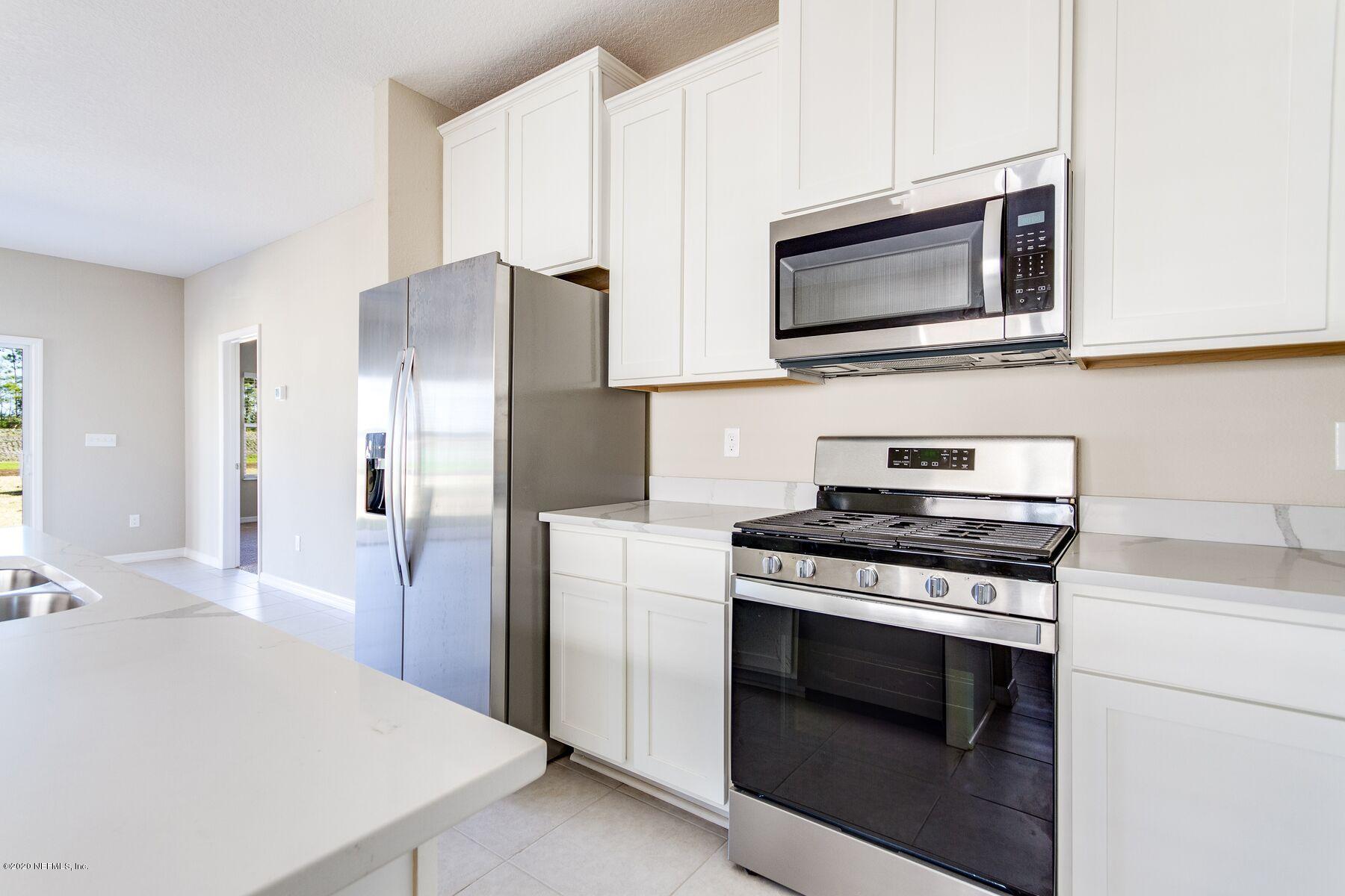 235 Brybar Drive St. Augustine, FL 32095 - Photo 6 of 11 a kitchen with stainless steel appliances a stove a microwave and white cabinets