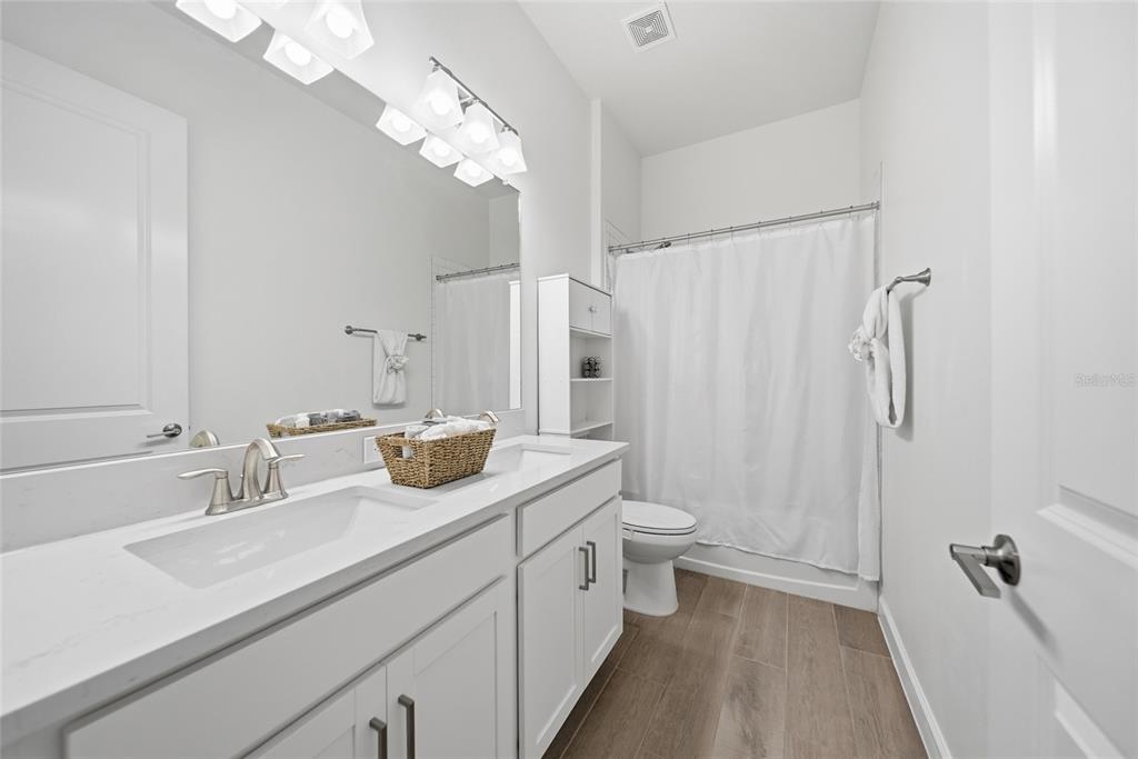 17301 Scuba Crest Street Wimauma, FL 33598 - Photo 15 of 37 a bathroom with a double vanity sink toilet and shower