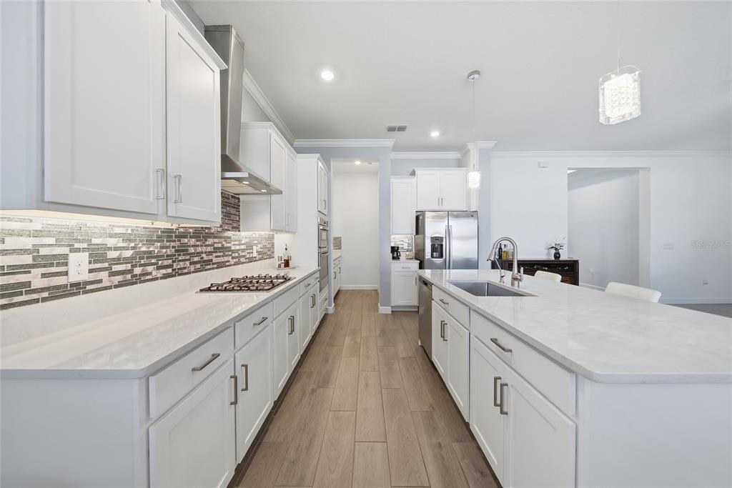 17301 Scuba Crest Street Wimauma, FL 33598 - Photo 5 of 37 a large white kitchen with kitchen island a sink a stove and a refrigerator