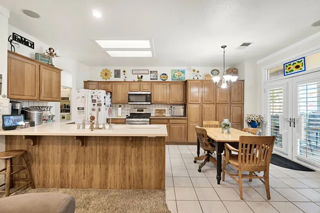 a kitchen with a dining table chairs and white appliances