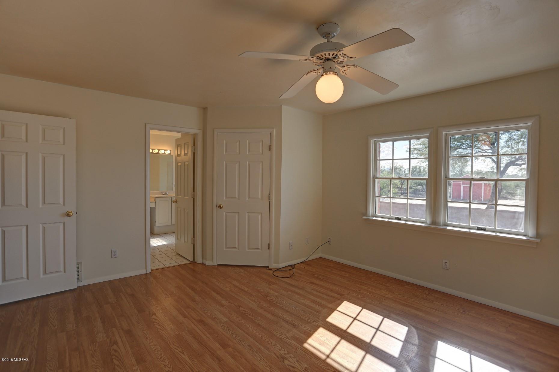 5851 South Avra Road Tucson, AZ 85735 - Photo 14 of 46 an empty room with wooden floor fan and windows