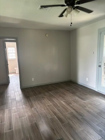 an empty room with wooden floor fan and window