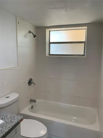 a bathroom with a granite countertop toilet a sink and a bathtub