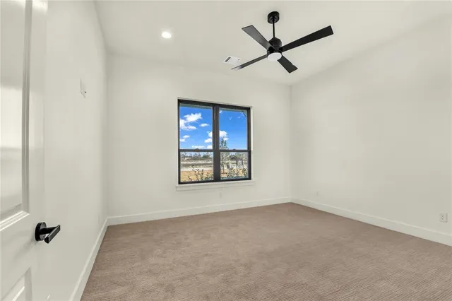 an empty room with a ceiling fan and window